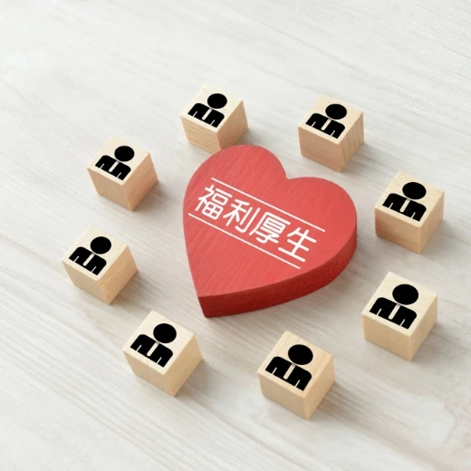 「福利厚生」と書かれた赤いハートの周りに並ぶ、人々を象徴 wooden block のアイコン