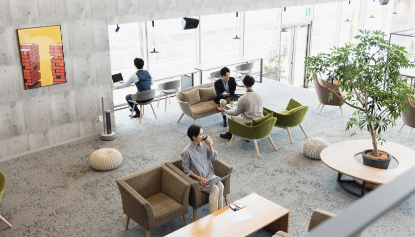 オープンなオフィス環境でリラックスして打ち合わせをする社員たち