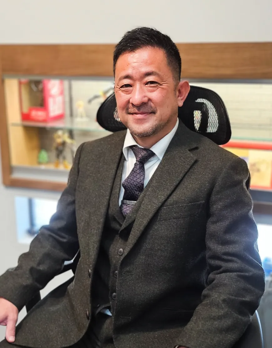 デスクに座り、穏やかな表情で微笑む代表者のポートレート