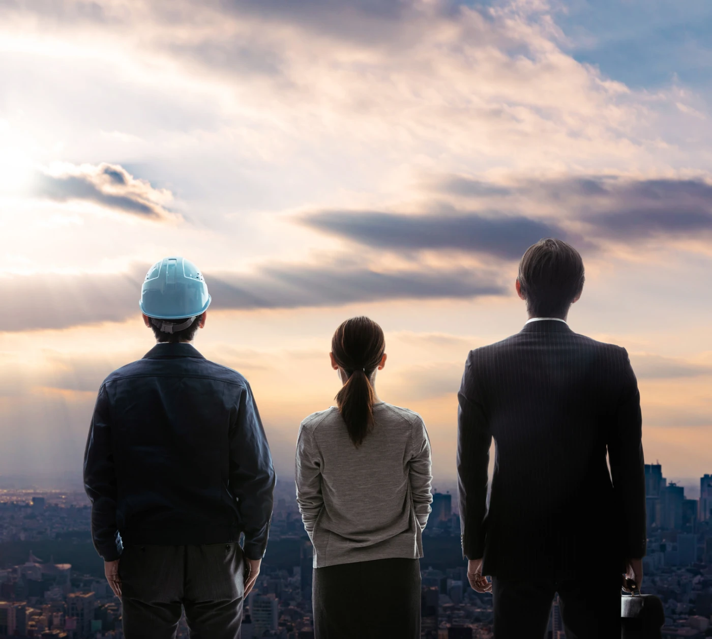 朝焼けの街を見下ろす作業員、女性、スーツ姿の男性のろしろ姿。未来への展望を象徴するイメージ