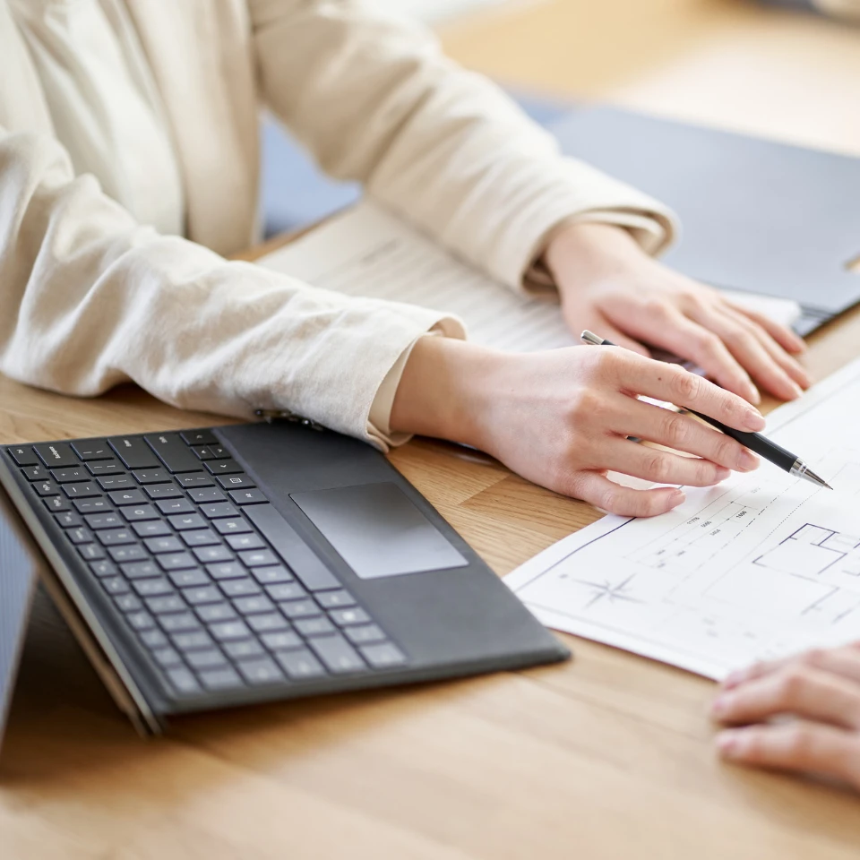 デスクで図面を指さしながら打ち合わせをするビジネスパーソンの手元