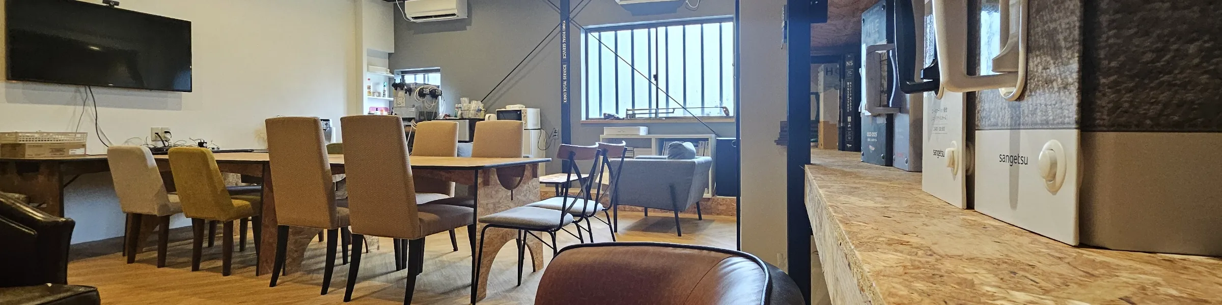 木目調のテーブルとモダンな椅子が並ぶ、開放的で落ち着いた雰囲気のオフィス休憩スペース・ラウンジ