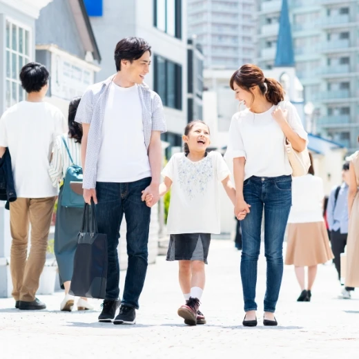 休日を家族で楽しみ、笑顔で街を歩く若い夫婦と小さな女の子